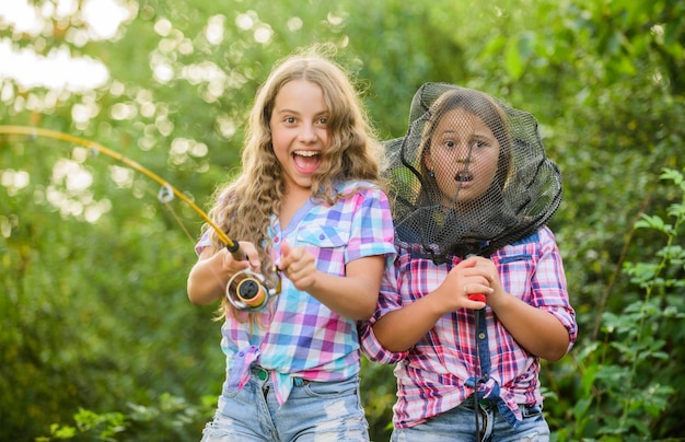 L'abbiamo beccato i bambini trascorrono il tempo al campo divertendosi pescatore di pesci due ragazze pescando pesca d'altura hobby estivo bambini felici con rete e canna vacanze estive fine settimana tempo di pesca a mosca