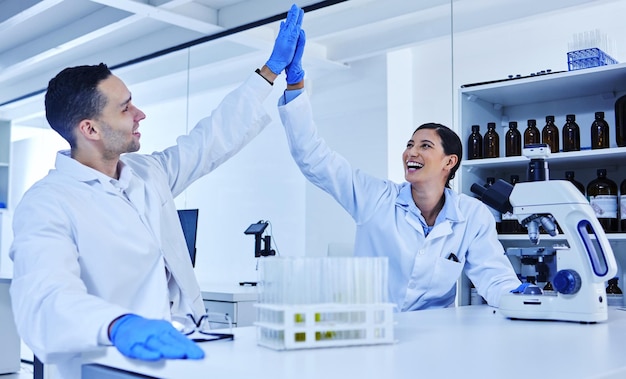 L'abbiamo fatto Foto ritagliata di due giovani scienziati che danno il cinque mentre lavorano nel loro laboratorio
