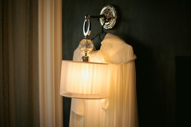 L'abito della sposa è appeso al muro nero. abito da sposa su un muro nero, su una lampada.