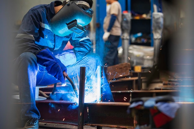 L'acciaio del metallo del lavoratore maschio della saldatura fa parte della struttura della trave