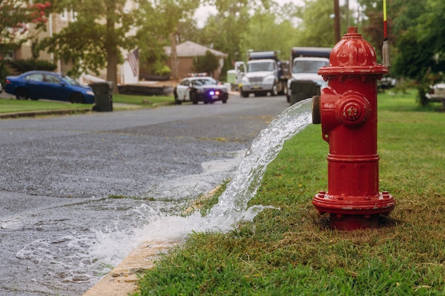 L'acqua che scorre da un idrante rosso aperto è bagnata dallo spray.