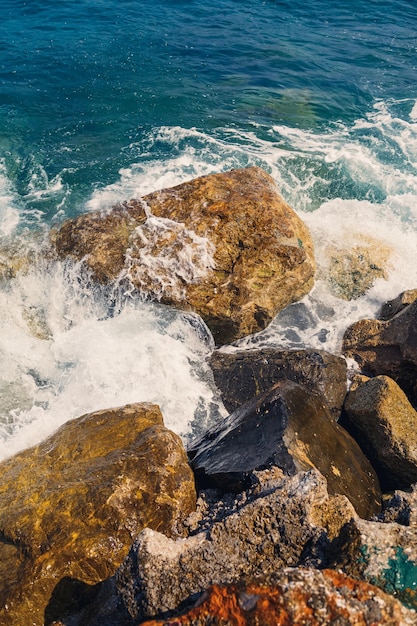 L'acqua del mare batte contro le rocce rocciose e fa onde con la schiuma