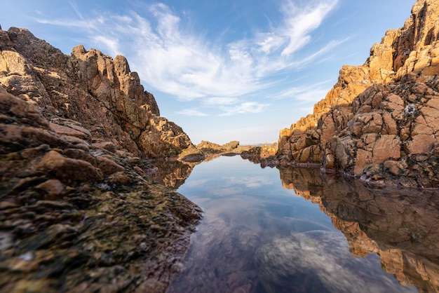 L'acqua del mare tra le scogliere riflette le scogliere gialle e il cielo blu