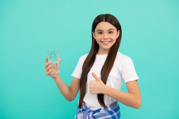 L'acqua della bevanda della ragazza teenager felice mantiene l'equilibrio idrico quotidiano nel corpo mostra il pollice in su, l'acqua quotidiana.