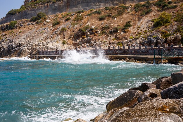 L'acqua di mare batte contro le rocce rocciose e fa le onde con la schiuma, molo robusto nel mare