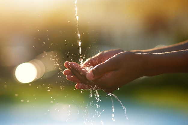 L'acqua è preziosa Colpo del primo piano delle mani tese sotto un flusso d'acqua