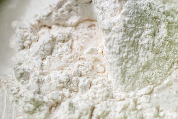 L'acqua viene aggiunta alla farina Impastare la pasta per la cottura Primo piano La farina e l'acqua vengono mescolate