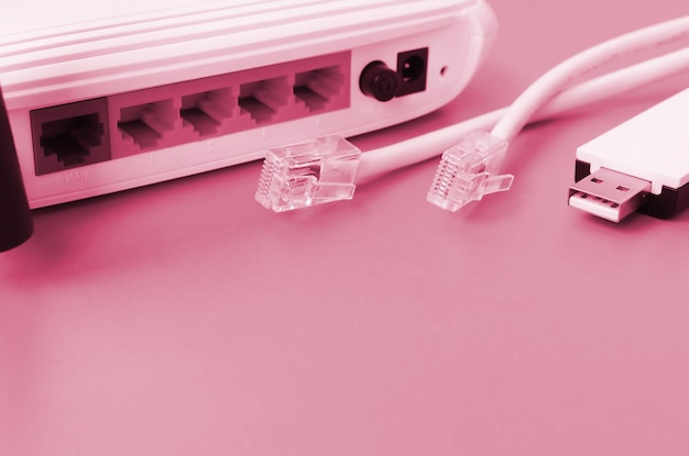 L'adattatore Wi-Fi USB portatile del router Internet e le spine del cavo Internet si trovano su uno sfondo arancione brillante Gli elementi necessari per la connessione a Internet Immagine tonica nel colore Viva Magenta dell'anno