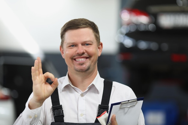 L'addetto al servizio di riparazione auto mostra il gesto ok con la mano e sorridendo