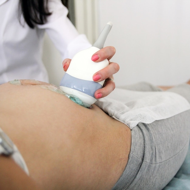 L'addome della donna felice durante un esame ecografico