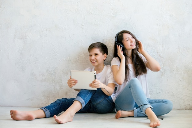 L'adolescente ascolta la musica seduto sul pavimento accanto a suo fratello con un tablet