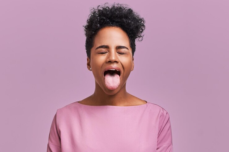 L'adolescente cattiva con i capelli afro fa cadere la mascella, sporgendo la lingua verso la telecamera in segno di disobbedienza, protesta e mancanza di rispetto. Emozioni umane, reazioni, sentimenti e atteggiamenti
