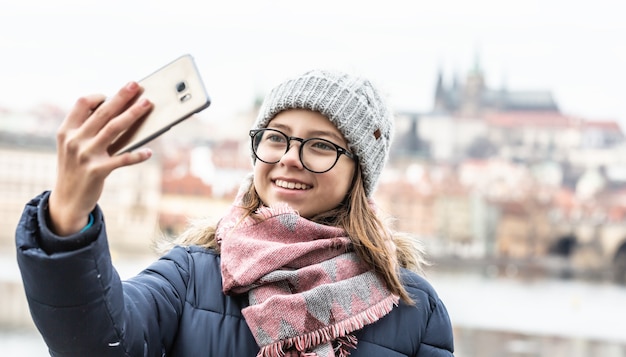 L'adolescente con gli occhiali si fa un selfie a Praga in una fredda giornata invernale.