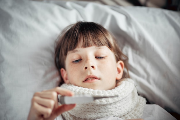 L'adolescente con un raffreddore misura la temperatura