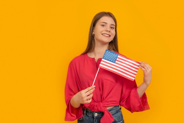 L'adolescente felice tiene una bandiera americana e sorride Studia l'istruzione inglese nelle scuole e nelle università degli Stati Uniti