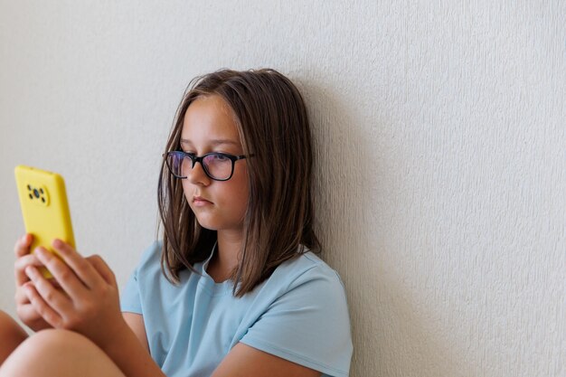 L'adolescente guarda il telefono su uno sfondo bianco