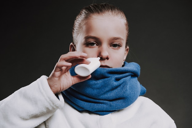 L'adolescente in maglia sciarpa gocciola gocce nel naso.