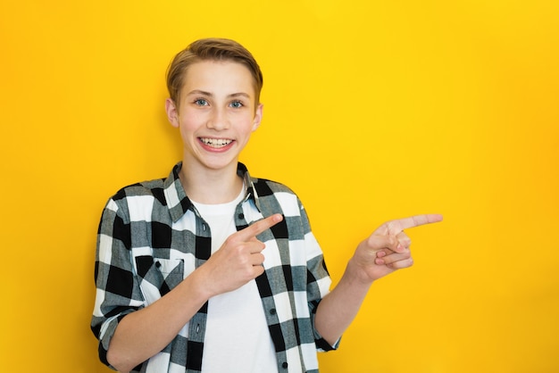 L'adolescente maschio felice soddisfatto indica nell'angolo in alto a destra, ha un piacevole sorriso a trentadue denti