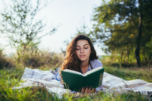 L'adolescente nostalgico è seduto nel parco e legge il libro