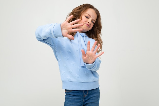 L'adolescente serio in maglia con cappuccio blu casuale rifiuta di attraversare le sue braccia davanti a se stessa su un bianco con lo spazio della copia