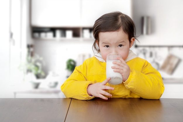 L'adorabile bambina fa colazione e beve yogurt con un cucchiaio