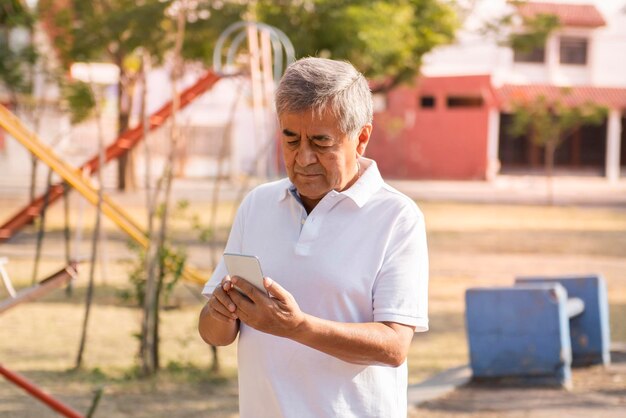 L'adulto anziano controlla la sua salute sul suo smartphone nel concetto di assistenza sanitaria personale del parco