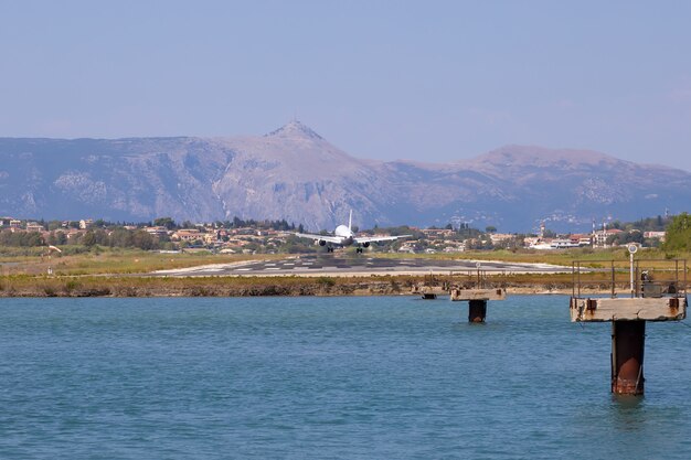 L'aereo del passeggero sta atterrando all'aeroporto di Kerkyra. La Grecia, l'isola di Corfù. Diminuzione in altezza. Pista sullo sfondo delle montagne e del mare.