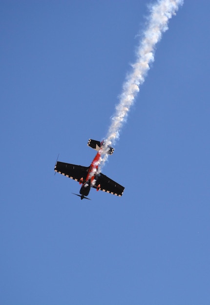 L'aereo militare vola dentro con il fumo nel cielo blu