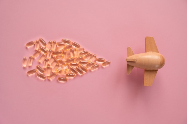 L'aereo sta trasportando capsule di olio di pesce su sfondo rosa