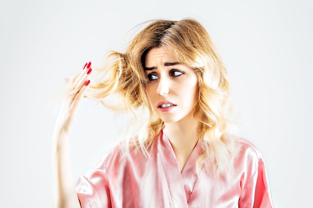 L'affascinante ragazza guarda con orrore le doppie punte dei suoi capelli.