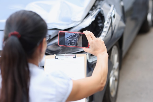 L'agente assicurativo sta filmando i danni alle conseguenze dell'auto del concetto di incidente stradale