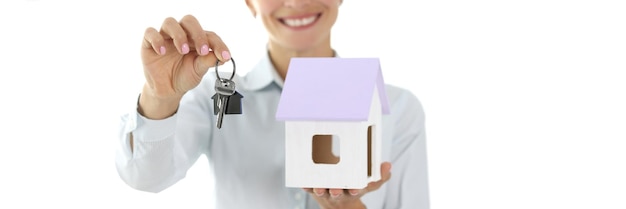 L'agente femminile sta tenendo la casa e la chiave acquistando casa a credito o ricevendo un concetto di edilizia sociale
