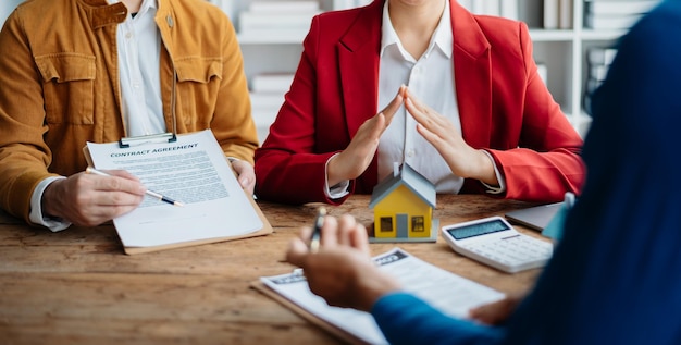 L'agente immobiliare femminile sta usando le mani per proteggere il tetto rosso per il concetto di investimento immobiliare sull'acquisto di case commerciali alla scrivania in ufficio xA