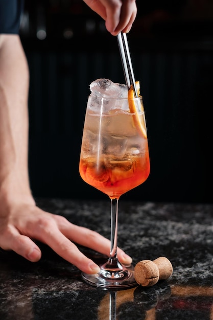 L'aggiunta di arancia in aperol spritz prepara un cocktail in un bar