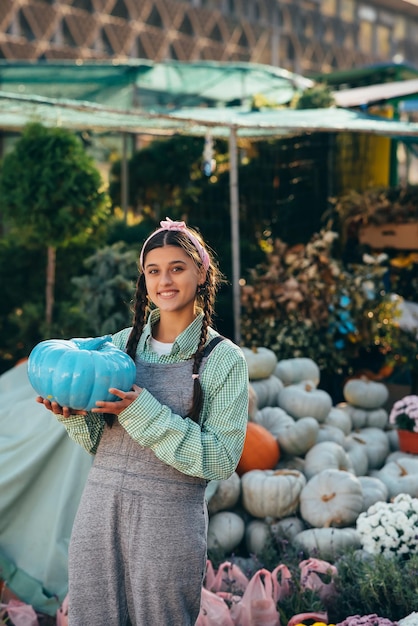 L'agricoltore femminile che tiene la zucca di colore blu ha decorato la zucca per le vacanze