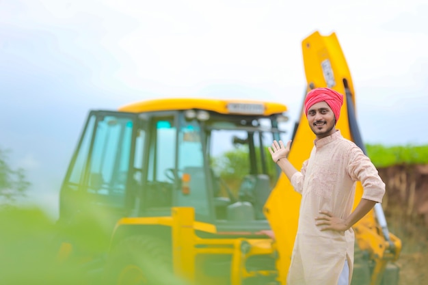 L'agricoltore indiano in piedi con la sua nuova macchina movimento terra.