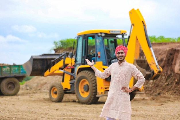 L'agricoltore indiano in piedi con la sua nuova macchina movimento terra.