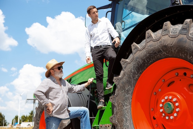 L'agricoltore professionista con un moderno trattore si combina in un campo alla luce del sole al lavoro