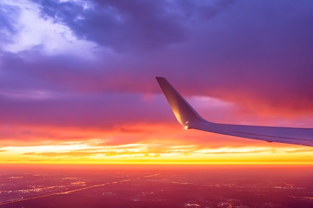 L'ala dell'aereo si è illuminata dal tramonto su un cielo coloful.