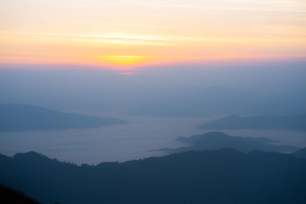 L'alba sulla montagna con la nebbia e le nuvole la coprono