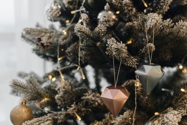 L'albero di Natale artificiale in un interno luminoso con i fiori d'argento nevica sui rami. Natale.