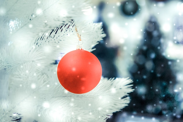 L'albero di Natale gioca con le decorazioni e il primo piano innevato dei rami dell'albero di Natale con nevicate, fiocchi di neve che cadono, macchie di colore bianco. Priorità bassa del nuovo anno di Natale di inverno.