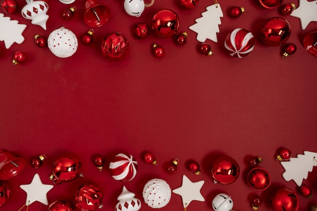 L'albero di Natale rosso gioca la decorazione su una priorità bassa rossa con lo spazio della copia. Disposizione di auguri di Capodanno. Stile minimal. Disteso.