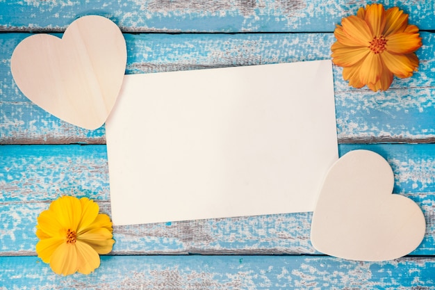 L&#39;album in bianco della struttura della foto decora con la forma del cuore e del fiore su vecchio fondo di legno blu