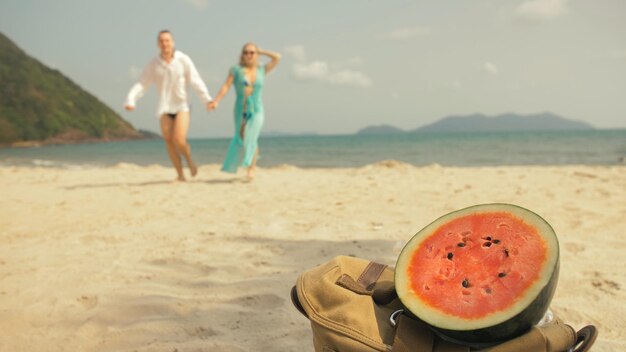 L'allegra coppia d'amore sfocata sullo sfondo di un cocomero sulla spiaggia di sabbia tropicale mare r