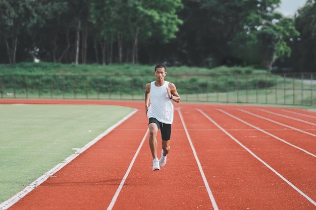 L'allenamento del corridore sportivo dell'atleta corre sulla corsia dello stadio al mattino Uomo del corridore che indossa un giubbotto bianco per esercitarsi a correre prepararsi per la gara di competizione Concetto di sport