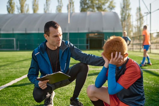 L'allenatore conforta il piccolo calciatore che piange dopo aver mancato il gol. Concetto di calcio per bambini