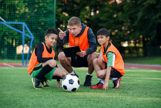 L'allenatore di calcio mostra una strategia di gioco del calcio ai suoi giocatori durante l'allenamento.