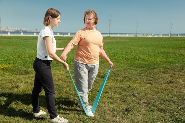 L'allenatore di giovani donne aiuta una donna anziana a fare esercizi di stretching
