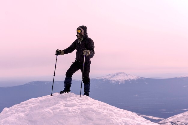 L'alpinista con maschera e occhiali antivento ha raggiunto la cima della montagna innevata